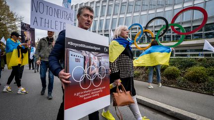 Des Ukrainiens marchent devant le siège du Comité international olympique (CIO), lors d'une manifestation contre la feuille de route proposée par le CIO pour organiser le retour à la compétition des athlètes russes et biélorusses sous un drapeau neutre, à Lausanne, le 25 mars 2023. (FABRICE COFFRINI / AFP)