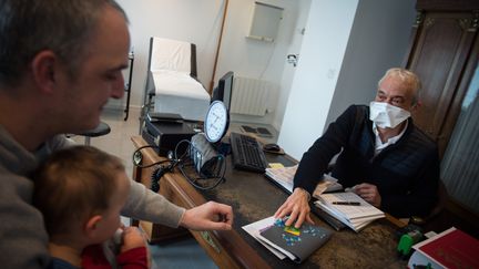 Un docteur porte un masque de protection durant l'examen médical d'un enfant, dans le Morbihan. (LOIC VENANCE / AFP)