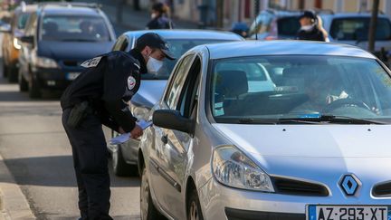 Un policier contrôle un automobiliste à Valence (Drôme), le 19 mars 2020. (NICOLAS GUYONNET / HANS LUCAS / AFP)