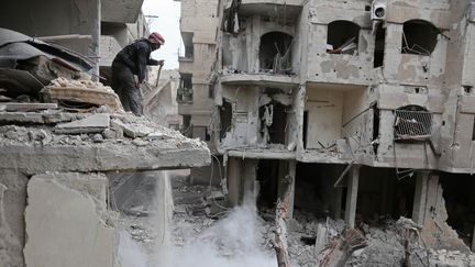 Un homme dans des décombres, dans la Ghouta orientale, dans la banlieue de Damas, la capitale syrienne, le 22 février 2018. (ABDULMONAM EASSA / AFP)