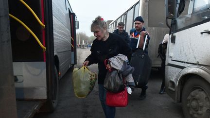 Des habitants sont vus devant un bus qui emmène des réfugiés d'Izium dans la région de Belgorod, en Russie, le 15 avril 2022. (RIA NOVOSTI / SPUTNIK / via AFP)