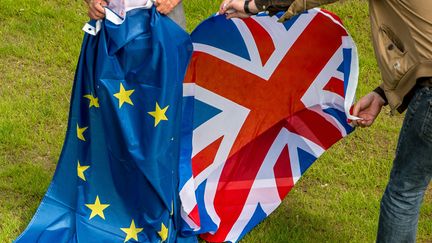 Deux personnes tiennent l'une un drapeau européen, l'autre un drapeau britannique, le 24 juin 2016 à Hardelot, dans le Nord de la France. (PHILIPPE HUGUEN / AFP)