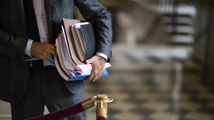 Un homme les bras chargés de dossiers à l'Assemblée.&nbsp; (JULIEN DE ROSA / MAXPPP)