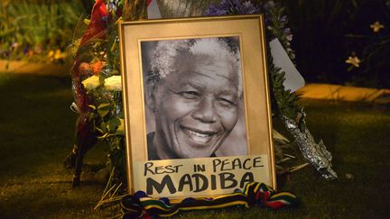 Un portrait de l'ancien pr&eacute;sident sud-africain Nelson Mandela est d&eacute;pos&eacute; au pied d'un arbre &agrave; Johannesbourg (Afrique du Sud), le 6 d&eacute;cembre 2013. (ALEXANDER JOE / AFP)