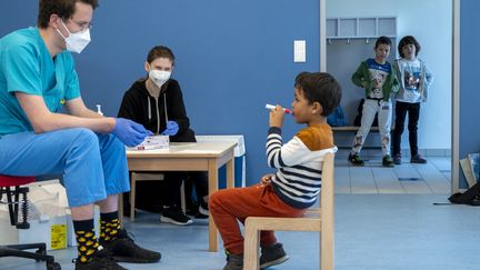 Une équipe médicale suit&nbsp;un garçon d'âge préscolaire qui utilise un nouveau test Covid-19 en forme de sucette avant de tester des enfants d'âge préscolaire au "City of Vienna Kindergarten" à Vienne, en Autriche, le 28 avril 2021.&nbsp; (JOE KLAMAR / AFP)