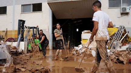 Des habitants de Paiporta, près de Valence (Espagne), tentent de nettoyer une rue recouverte de boue, le 31 octobre 2024, après des inondations. (MANAURE QUINTERO / AFP)