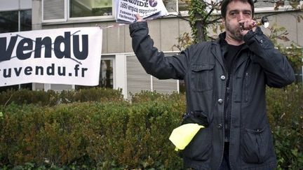 Un salarié de Paru Vendu brandit un faux journal titrant "Paru vendu liquidé", le 3 novembre 2011. (JEAN-PHILIPPE KSIAZEK / AFP)