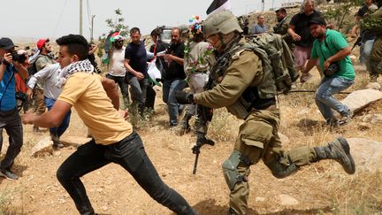 Un soldat israélien chasse des manifestants palestiniens, le 13 mai 2022 à Masafer Yatta (Cisjordanie). (MOSAB SHAWER / AFP)