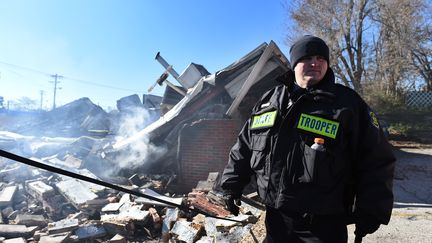 Un policier garde les d&eacute;bris encore fumants d'un b&acirc;timent incendi&eacute; par des &eacute;meutiers dans la nuit du 24 au 25 novembre. (JEWEL SAMAD / AFP)