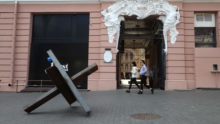 Des personnes passent devant des obstacles antichars dans le centre-ville d'Odessa, dans le sud de l'Ukraine, le 5 avril 2022. (OLEKSANDR GIMANOV / AFP)