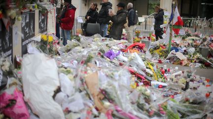 A Paris, &agrave; la veille de la gigantesque marche annonc&eacute;e, des passants continuent de d&eacute;poser des gerbes de fleurs devant le si&egrave;ge de "Charlie Hebdo", en hommage aux douze personnes mortes dans l'attaque du journal satirique. (FREDRIK VON ERICHSEN / DPA / AFP)