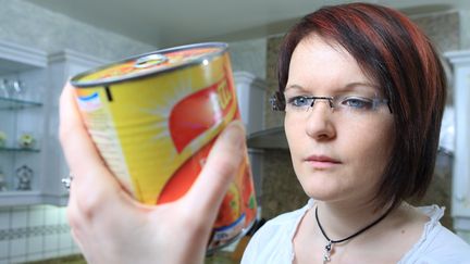 Une femme lit la liste des ingrédients d'une boîte de conserve pour vérifier qu'elle ne comporte aucun produit allergène. (PHILIPPE TURPIN / MAXPPP)