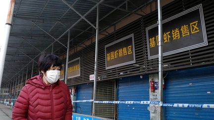 Une femme passant devant le marché de Wuhan (Chine), le 12 janvier 2020. (NOEL CELIS / AFP)