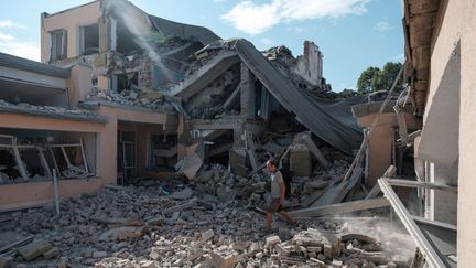 Un enseignant marche parmi les ruines d'une école détruite à la suite d'un bombardement à Bakhmut, dans la région de Donetsk, le 24 juillet 2022. (IGOR TKACHEV / AFP)