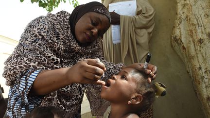 Une consultante de l'Unicef administre le vaccin antipoliomyélitique oral (VPO) à un enfant à Hotoro-Kudu (Nigeria), le 22 avril 2017, dans le cadre d'une campagne de vaccination synchronisée au sein de 13 pays d'Afrique centrale et d'Afrique de l'Ouest. (PIUS UTOMI EKPEI / AFP)