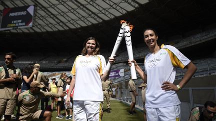 Les&nbsp;volleyeuses brésiliennes Ana Flavia (aujourd'hui retraitée) et Sheilla Castro avec la flamme olympique, le 14 mai 2016 au stade Mineirao de Belo Horizonte (Brésil). (DOUGLAS MAGNO / AFP)