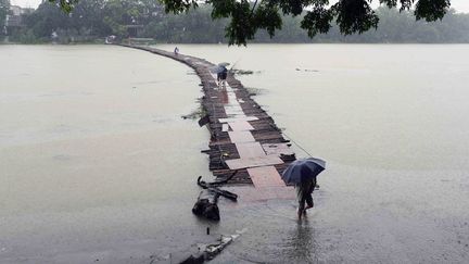 Des&nbsp;personnes traversent un pont en bois presque totalement submerg&eacute; &acirc;r les inondations &agrave;&nbsp;Guilin (Chine), le 19 ao&ucirc;t 2014. (AFP)