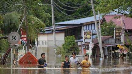 Des habitants marchent dans une rue inondée à Hulu Langat, en Malaisie, le 19 décembre 2021. (VINCENT THIAN / AP / SIPA)