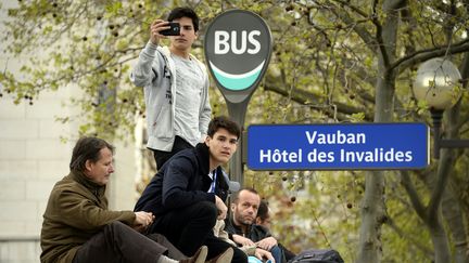 Des spectateurs sont juchés sur un abribus pour tenter de voir la course de Formula E, à Paris, le 23 avril 2016. (BERTRAND GUAY / AFP)