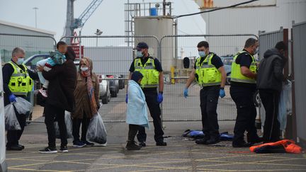 Une famille de migrants est escortée par des garde-frontières britanniques, le 20 septembre 2021, dans le port de Douvres (Royaume-Uni),&nbsp;après avoir traversé la Manche. (YANN THOMPSON / FRANCEINFO)