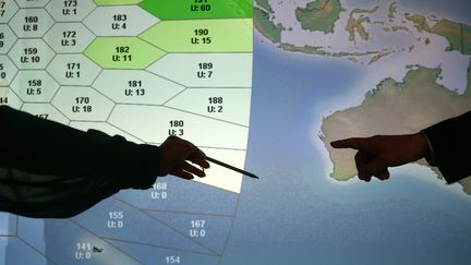 Des employ&eacute;s du groupe britannique Inmarsat montrent la zone o&ugrave; le Boeing disparu est soup&ccedil;onn&eacute; d'avoir fini sa course, le 25 mars 2014. (ANDREW WINNING / REUTERS)