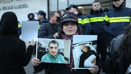 Une manifestante brandit les portraits de personnes victimes de violences lors des manifestations antigouvernementales, le 10 décembre 2024 devant le ministère de l'Intérieur, à Tbilissi (Géorgie). (FABIEN MAGNENOU / FRANCEINFO)