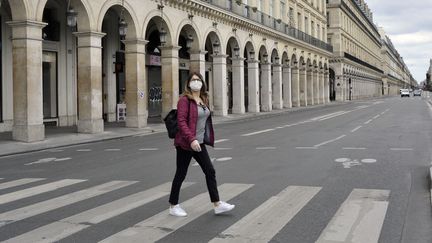 Une passante masquée traverse une rue de Paris, le 13 novembre 2021. (SERGE ATTAL / ONLY FRANCE / AFP)