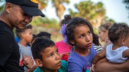 Des enfants migrants se rassemblent après qu'un volontaire ait ouvert une boîte contenant des animaux en peluche qui avaient été donnés près de la frontière mexicaine à Matamoros, le 29 juin 2019.&nbsp; (SERGIO FLORES / AFP)