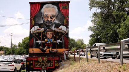 Une&nbsp;fresque murale représentant Emmanuel Macron en marionnette manipulée par le Jacques Attali, le 23 juin 2022 à Avignon. (ESPOSITO ANGE / MAXPPP)