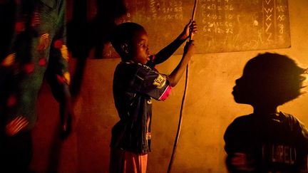 Dans la région de Porto-Novo, il n’y a pas d’électricité. La famille Honnon, le père Joseph, sa femme Windsy et leurs quatre enfants, s’éclairent avec des lampes à pétrole nocives pour les yeux et pour la santé en général, en raison de la fumée toxique qu’elles dégagent. Chaque soir, Joseph aide ses enfants Rogathien et Eveline dans la révision de leurs leçons. A cet effet, il leur a installé un tableau à craie. (Pascal Maitre/Cosmos)