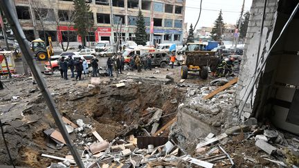 Des secouristes déblayent les décombres d'un cratère près d'un hôtel détruit après une attaque de missile à Kharkiv (Ukraine), le 11 janvier 2024. (SERGEY BOBOK / AFP)