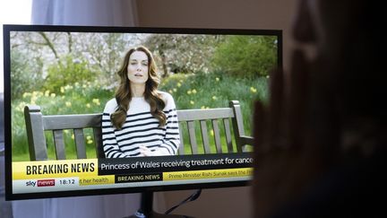 Une personne regarde la vidéo de Kate Middleton qui annonce être atteinte d'un cancer, sur la chaîne Sky News à Londres (Royaume-Uni), le 22 mars 2024. (RASID NECATI ASLIM / ANADOLU / AFP)