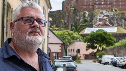 Eric Weiss, salarié de General Electric, devant&nbsp;une banderole posée en soutien aux salariés de General Electric, au pied du Lion de Belfort (Territoire de Belfort), le 21 juin 2019. (GUILLEMETTE JEANNOT / FRANCEINFO)