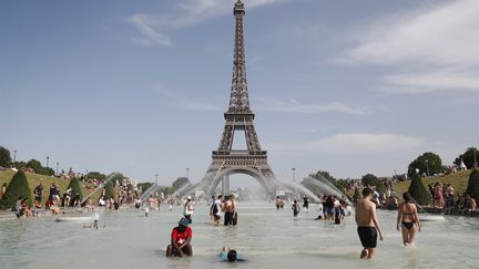 Des personnes se baignent dans la fontaine du Trocadéro à Paris, le 28 juin 2019. (ZAKARIA ABDELKAFI / AFP)