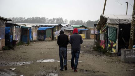 Deux migrants marchent dans l'une des artères de la "jungle" de Calais, le 23 octobre 2016. (SIPANY / SIPA)