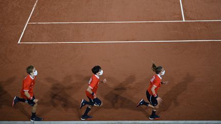 Des ramasseurs de balles courent sur le court de tennis le troisième jour de Roland-Garros à Paris, le 29 septembre 2020. (ANNE-CHRISTINE POUJOULAT / AFP)