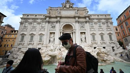 Des touristes portent des masques de protection devant la fontaine de Trevi, dans le centre de Rome, le 3 mars 2020. (ALBERTO PIZZOLI / AFP)