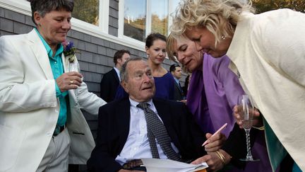 L'ancien pr&eacute;sident am&eacute;ricain George Bush signe des documents officiels lors d'un mariage entre deux femmes, le 21 septembre 2013 aux Etats-Unis.&nbsp; (SUSAN BIDDLE / AP /SIPA)