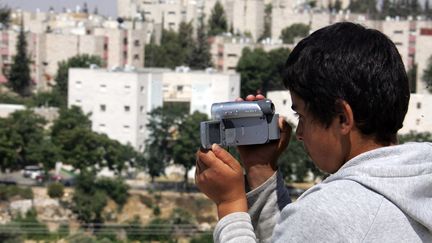 Un jeune Palestinien utilise une caméra, distribuée par l'ONG&nbsp;B'Tselem à sa famille, en 2008 près d'Hébron en Cisjordanie. (HAZEM BADER / AFP)