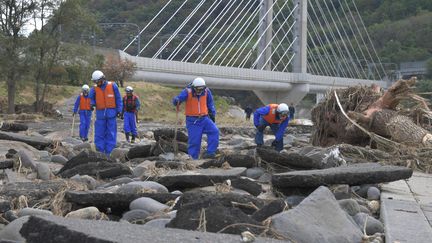 Des policiers cherchent des survivants parmi les décombres après le débordement de la rivière Chikuma, à Ueda, dans la préfecture de Nagano, le 15 octobre 2019. (YOICHI HAYASHI / YOMIURI / AFP)