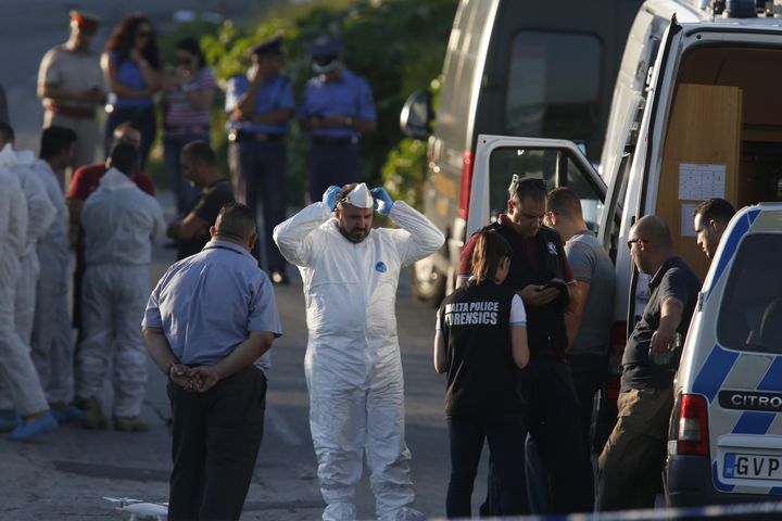 Des policiers&nbsp;ont examiné les preuves matérielles, sur la route et dans le champ où a été retrouvée la carcasse du véhicule. (DARRIN ZAMMIT LUPI / REUTERS)