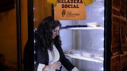 Une restauratrice de Buenos Aires, Maria Belen Aragon, remplit son «réfrigérateur social» de plats préparés qu'elle distribue aux pauvres et aux sans-abri. (JUAN MABROMATA / AFP)