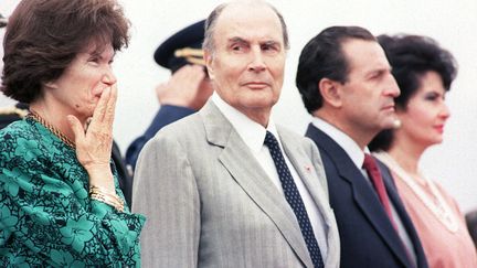 Le pr&Egrave;sident de la R&eacute;publique fran&ccedil;aise Fran&ccedil;ois Mitterrand (C) regarde son &eacute;pouse Danielle Mitterrand (G) prise de fou rire pendant les hymnes nationaux jou&eacute;s &agrave; leur arriv&eacute;e &agrave; l'a&eacute;roport de Quito (Equateur), le 11 octobre 1989. (DANIEL JANIN / AFP)