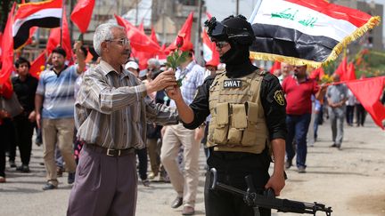 A Bagdad (Irak), le parti communiste a aussi c&eacute;l&eacute;br&eacute; le 1er mai. Un civil a m&ecirc;me offert un brin de muguet &agrave; un policier. (AHMAD AL-RUBAYE / AFP)