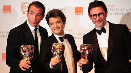 L'acteur Jean Dujardin, le producteur de "The Artist" Thomas Langmann et le r&eacute;alisateur du film, Michel Hazanavicius avec leurs Bafta Awards, le 12 f&eacute;vrier 2012. (LEON NEAL / AFP)