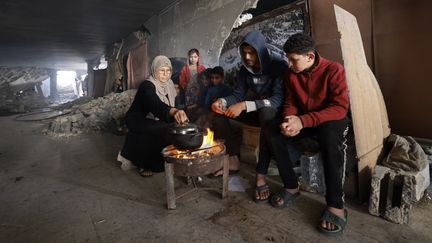 Des Palestiniens déplacés par la guerre préparent de la nourriture dans un bâtiment détruit de Rafah, dans la bande de Gaza, le 17 janvier 2024. (AFP)