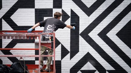 Un assistant de l'artiste murale Caroline Monnet peint pendant le festival de la murale à Montréal, au Québec, le 16 juin 2022. (PAOLA CHAPDELAINE / AFP)