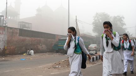 Des écolières indiennes couvrent leur visage pour se protéger de la pollution à New Delhi (Inde), le 8 novembre 2017. (SAJJAD HUSSAIN / AFP)