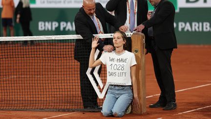 "Nous avons 1028 jours restants". Cette activiste environnementale adresse un message à tout le court Philippe-Chatrier, enchaînée au filet en pleine demi-finale Casper Ruud - Marin Cilic. Des démonstrations d'opinion de plus en plus nombreuses ces dernières semaines dans le monde du sport (THOMAS SAMSON / AFP)