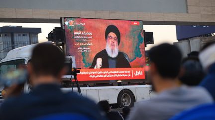 Des personnes écoutent le discours du secrétaire général du Hezbollah, Hassan Nasrallah, sur le conflit entre Israël et le Hamas, sur un écran installé sur la place Tahrir à Bagdad, en Irak, le 3 novembre 2023. (MURTADHA AL-SUDANI / ANADOLU / AFP)